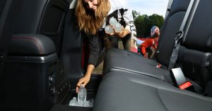 A woman grabbing water bottles out of the floor compartment in the back seat of the 2019 Dodge Journey